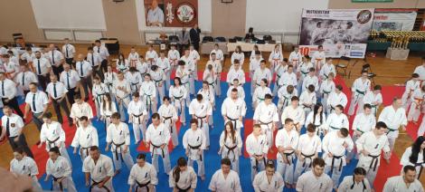 Zdjęcie nr 1 (5)
                                	                             sportowcy karate w białych kimonach stojący na sali gimnastycznej
                            